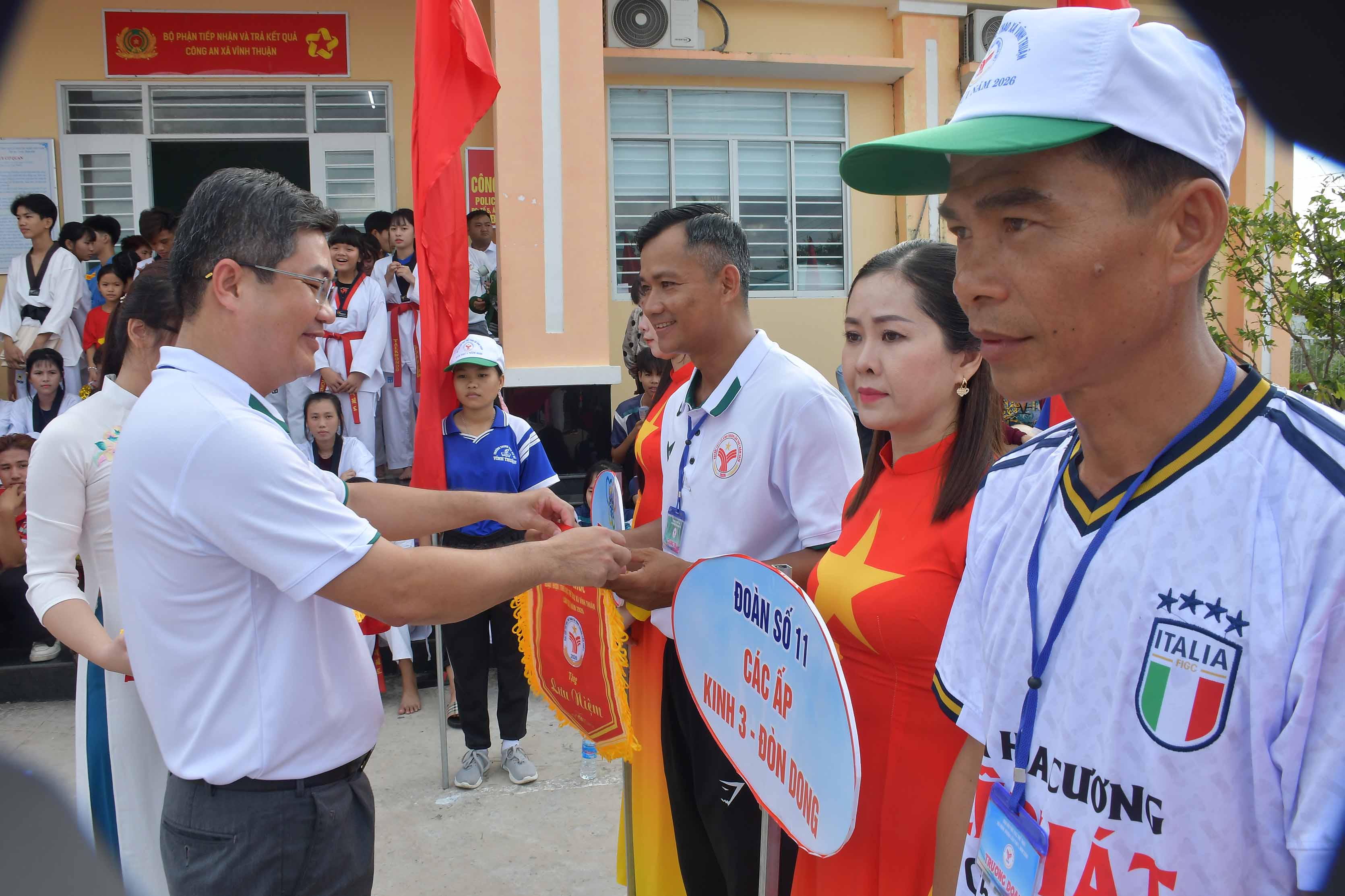 Huỳnh Ngọc Nguyên, Phó Bí thư Đảng ủy xã, Chủ tịch UBND xã, Trưởng Ban Tổ chức Đại hội Thể dục thể thao xã Vĩnh Thuận trao cờ lưu niệm cho các Đoàn